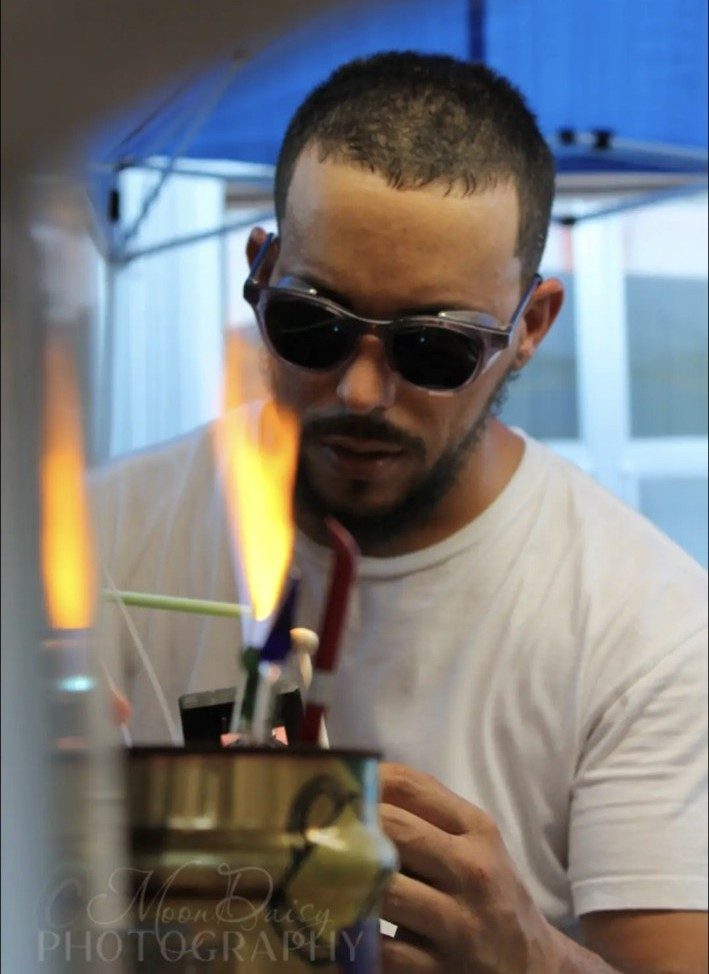 Jose Valdes working borosilicate glass behind the torch flame